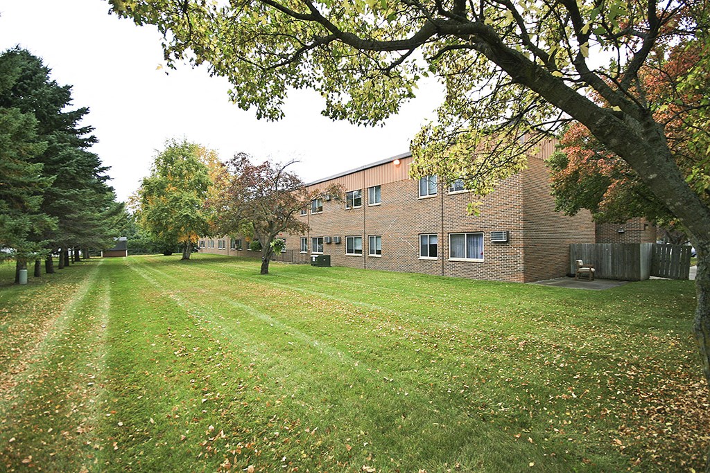 a large brick building with a green lawn and trees