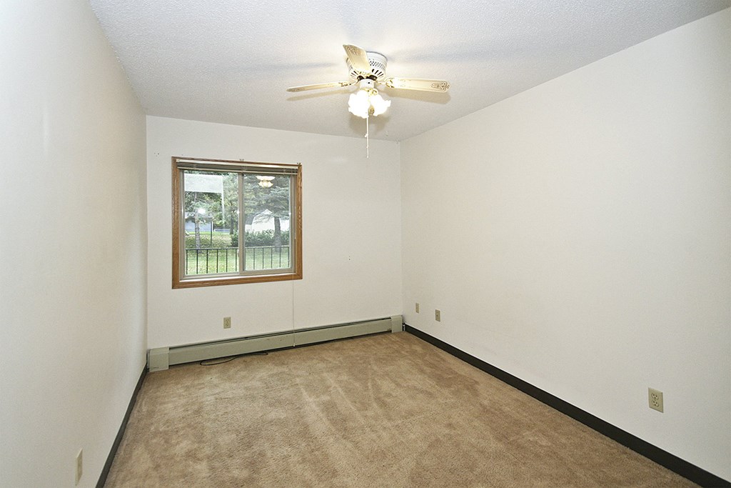 an empty living room with a ceiling fan and a window