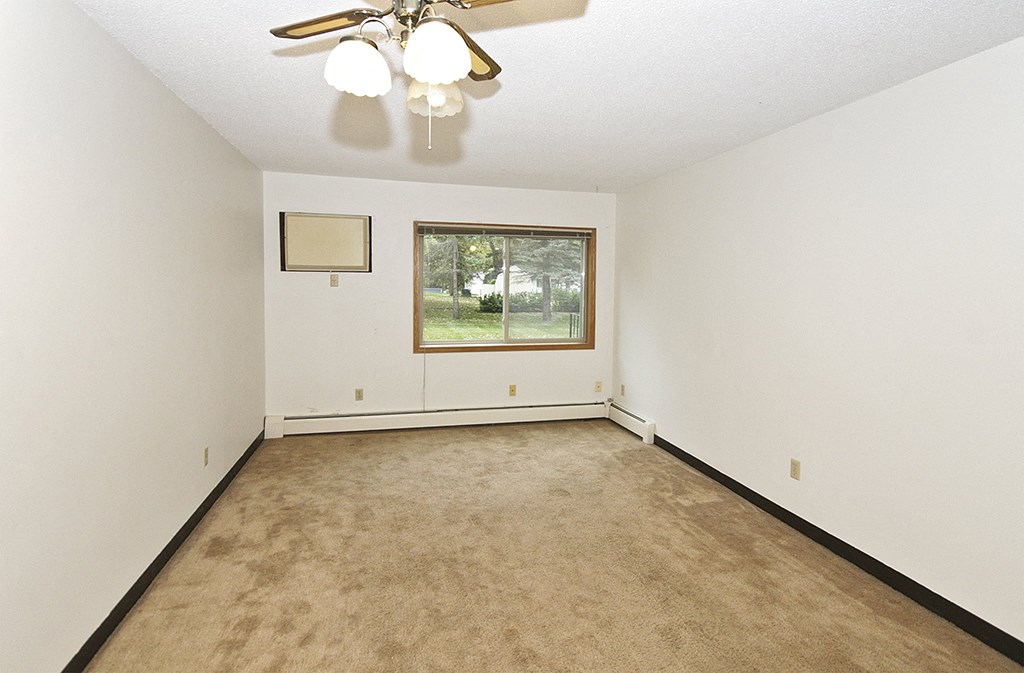 an empty living room with a ceiling fan and a window