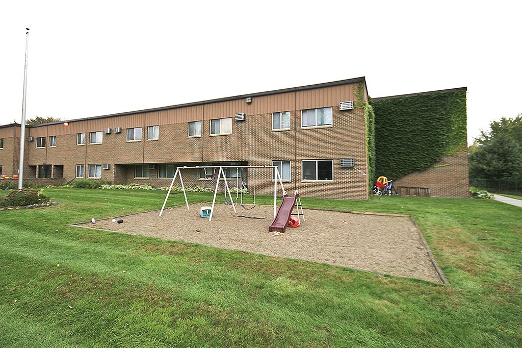 an empty playground in front of a brick building