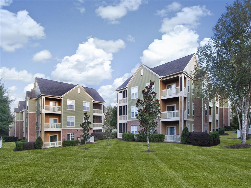 Meticulously maintained grounds with mature trees surround the soft green paint and brick exterior apartment homes at Alden Place at South Square Apartments, Durham, NC 27707