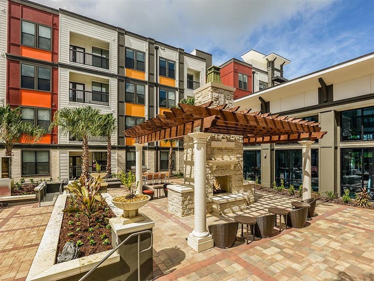Beautiful Outdoor Stone Fireplace with Lounge Seating to Enjoy with Friends and Family at EOS Apartments, Orlando, FL 32826