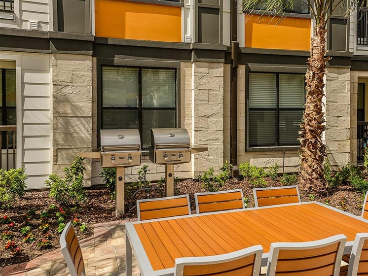 Outdoor Gourmet BBQ Gas Grilling Area with Fireplace to Enjoy a Wonderful Night with Friends and Family at EOS Apartments, Orlando, FL 32826