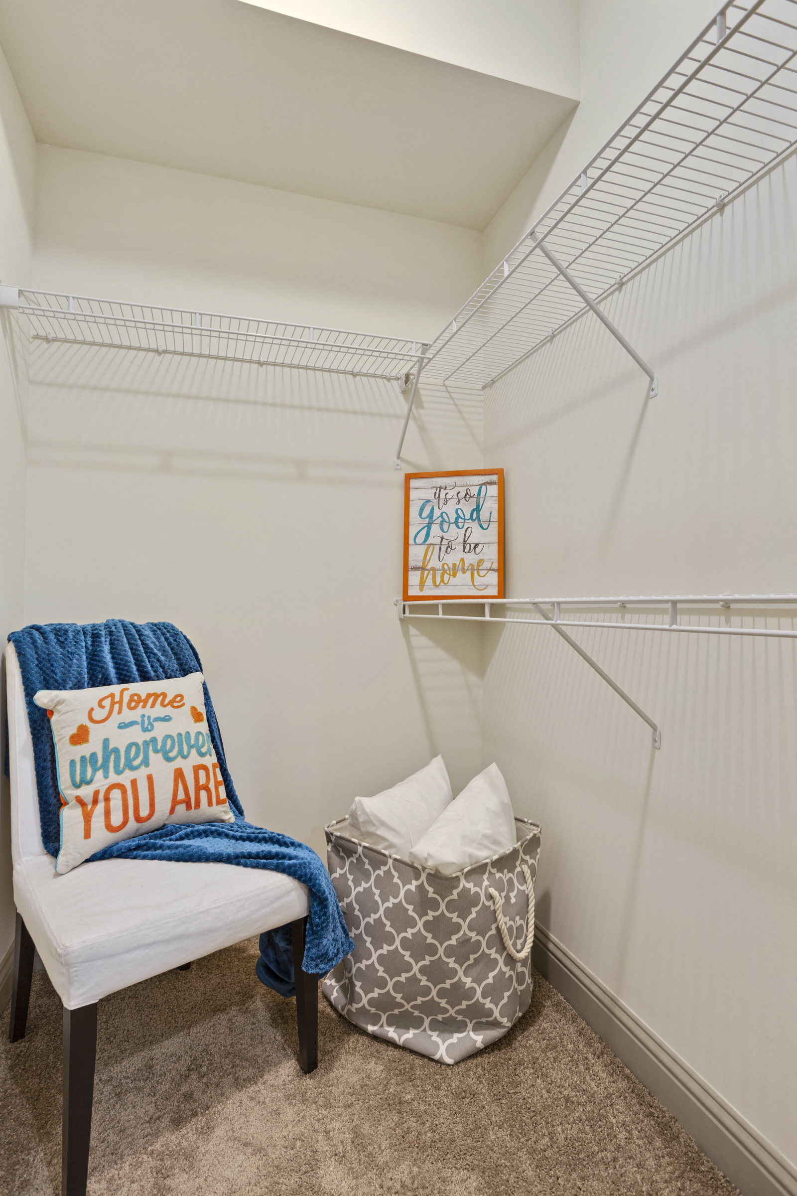 a walk in closet with a chair and a basket on the floor