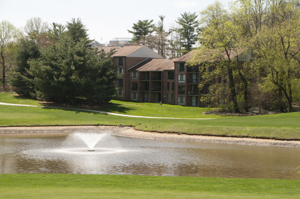 a pond with a fountain in front of an apartment building
