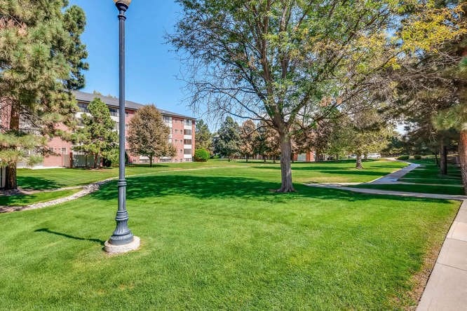 a green lawn with trees and a street light
