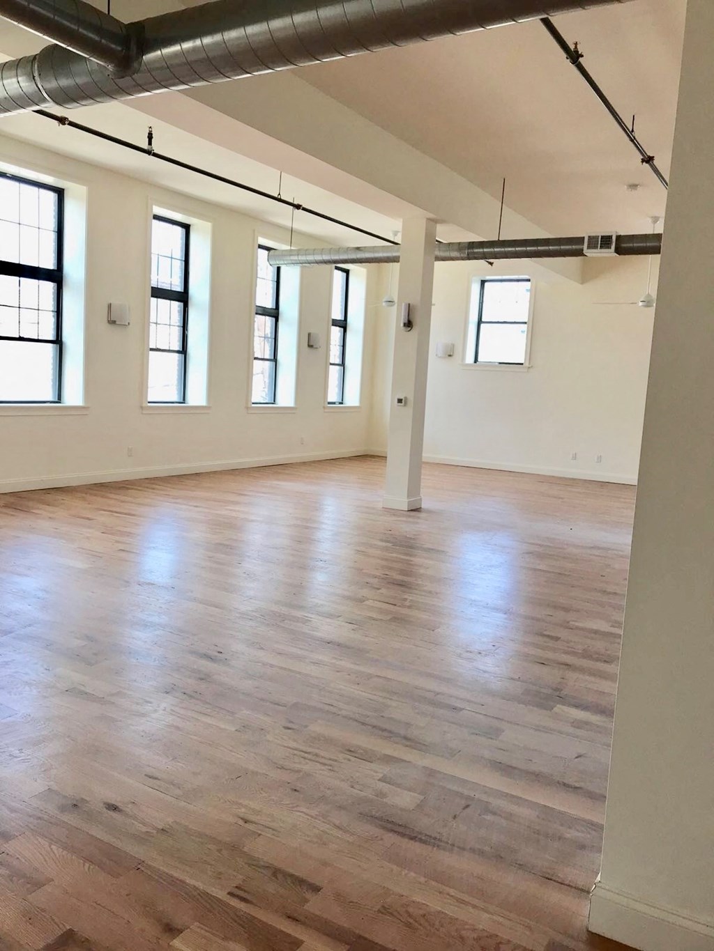 an empty room with a hard wood floor and white walls