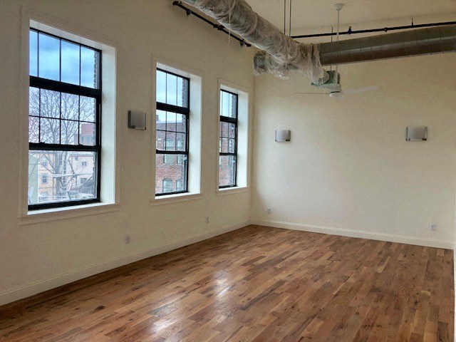 an empty room with a hard wood floor and three windows