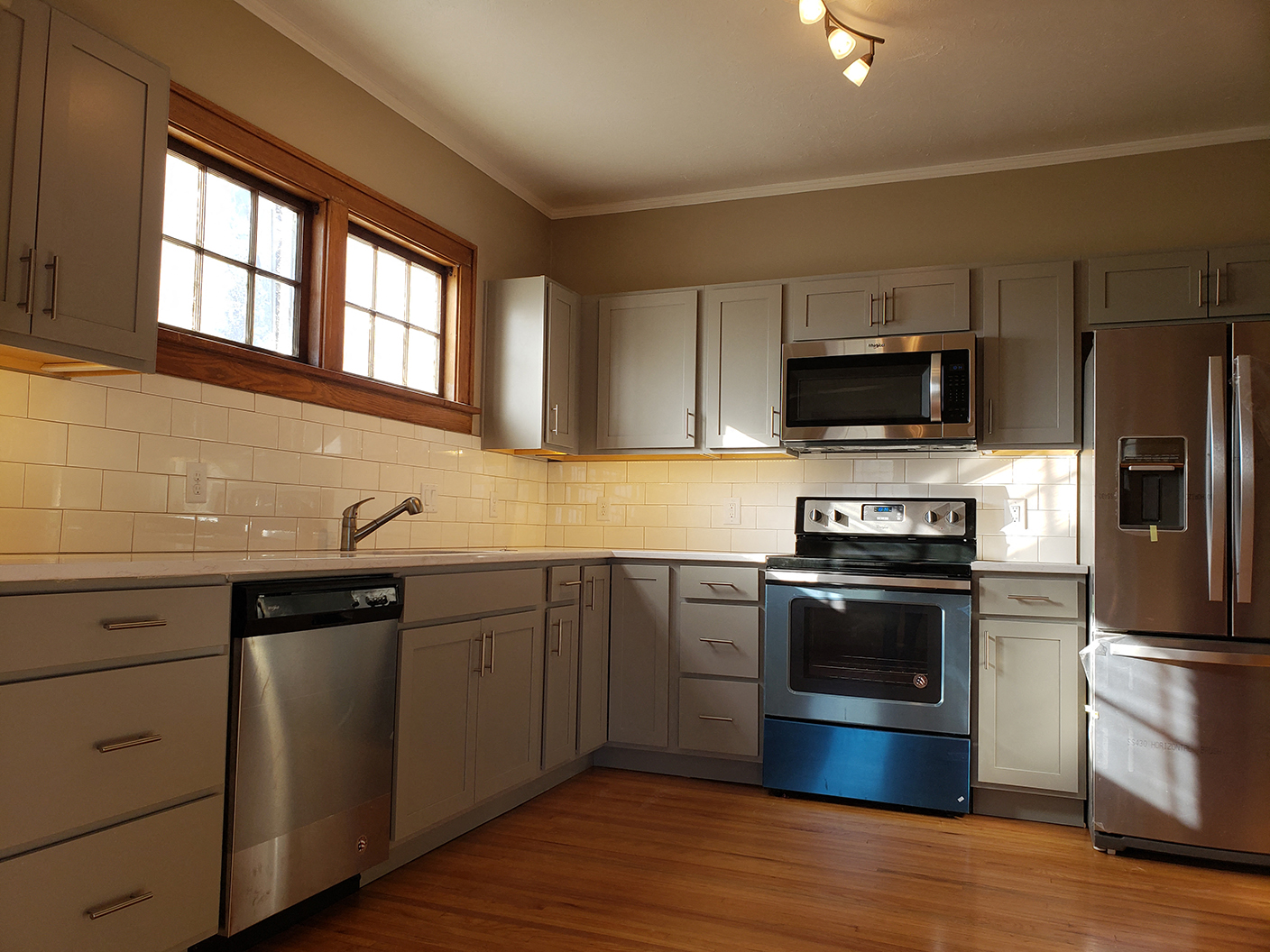 an empty kitchen with stainless steel appliances and white cabinets