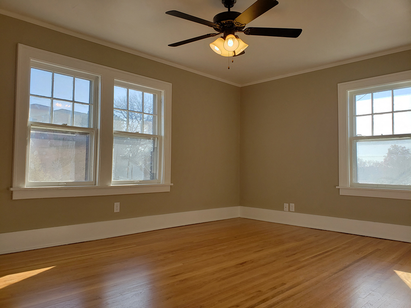 an empty room with a ceiling fan and three windows