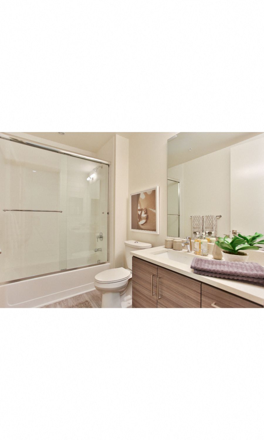 Old Town Scottsdale Apartments - Bathroom With a Quartz Vanity, Designer Fixtures, Modern Custom-Wood Cabinetry, Wood-Style Flooring, And A Shower With Tub.