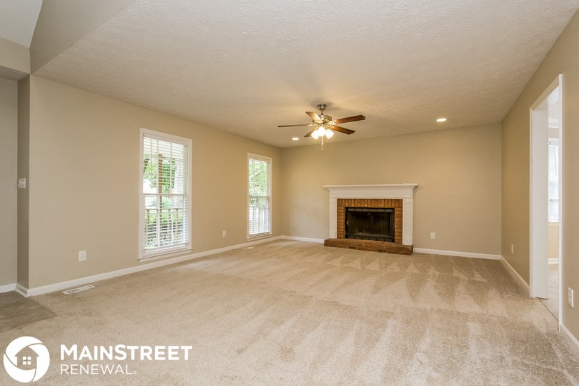 an empty living room with a fireplace and a ceiling fan