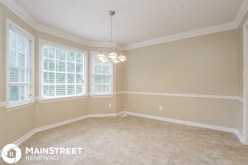 an empty dining room with three windows and a tiled floor