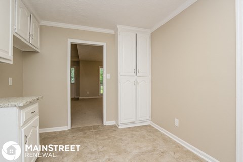 a kitchen with white cabinets and a door to a hallway