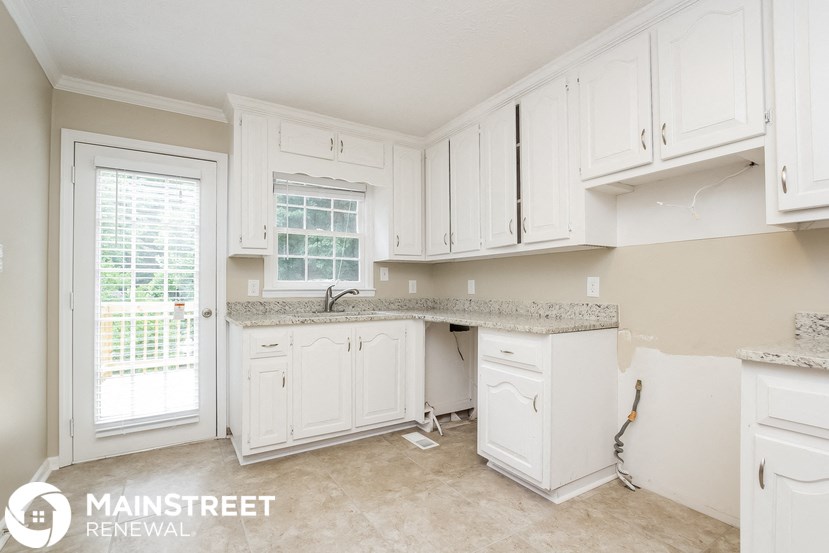 a kitchen with white cabinets and a sink and a window