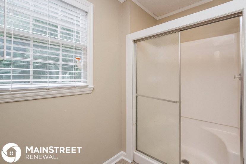 a white shower in a bathroom next to a window