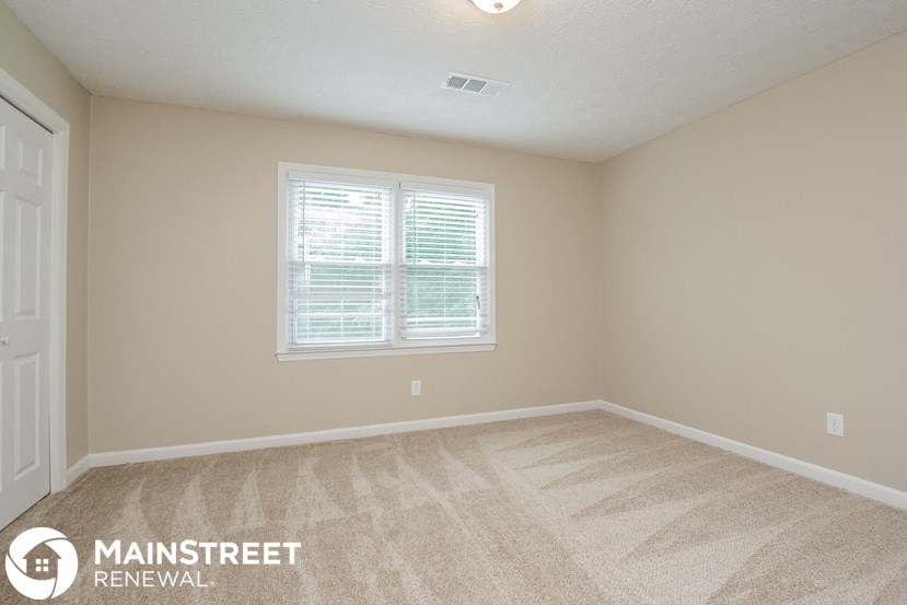 the upstairs bedroom has a large window and carpeted flooring
