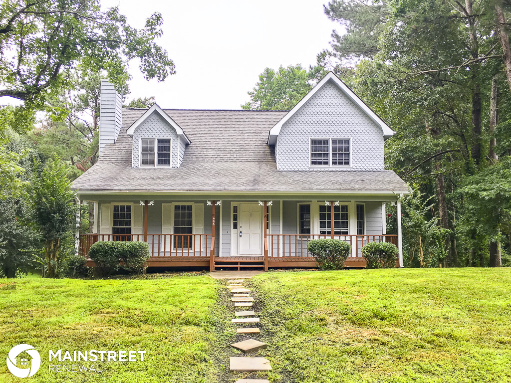 the front of a white house with a lawn and trees