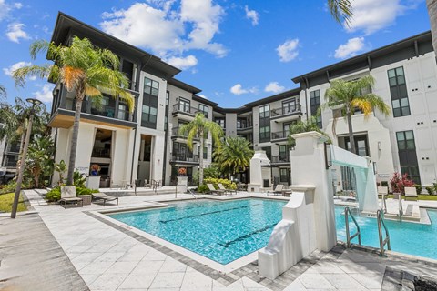 A swimming pool is surrounded by a white concrete patio and a white staircase.