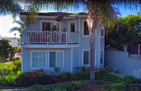 a white house with a balcony and a palm tree