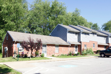 A row of houses with a car parked in front of the first one.