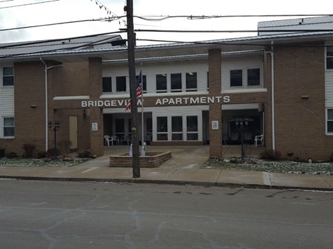 The front of the Bridgeview Apartments building with a sign and an American flag.