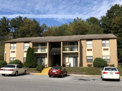 A large apartment building with cars parked in front.