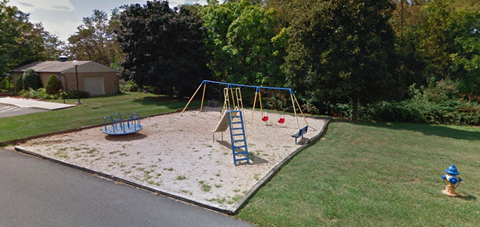 A playground with a blue swing set and a yellow fire hydrant.