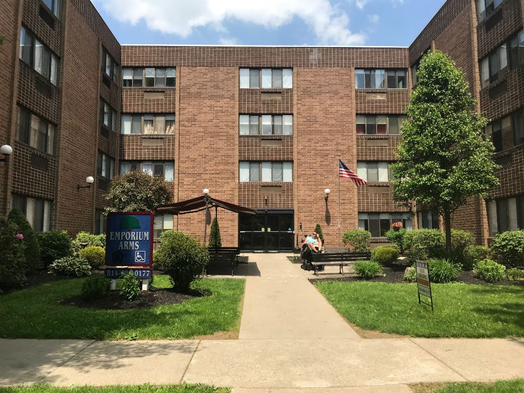 a man sitting on a bench in front of an apartment building