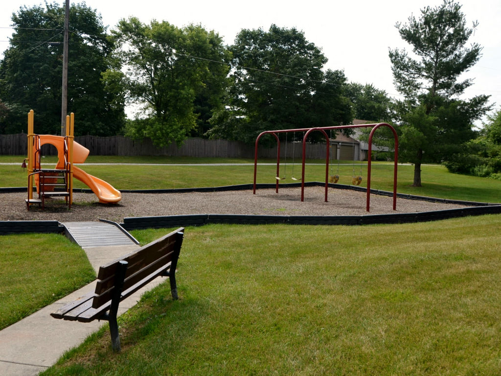 A playground with a slide, swings, and a bench.