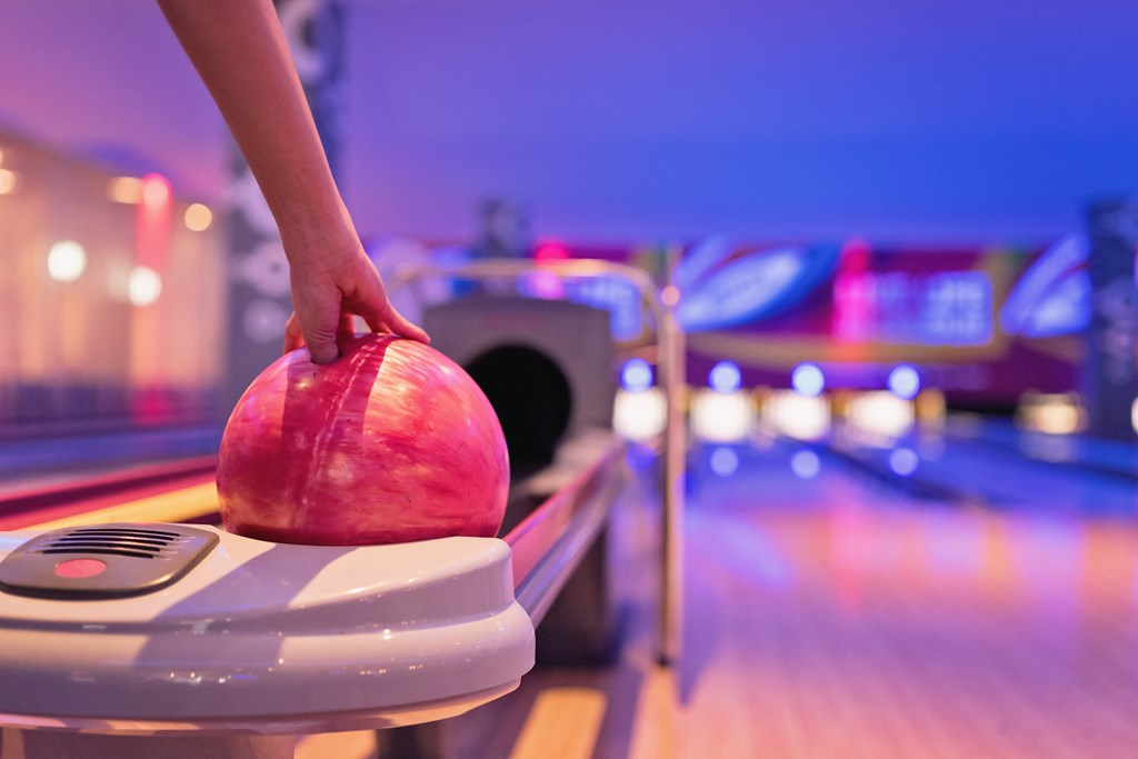 a person holding a bowling ball on top of a bowling