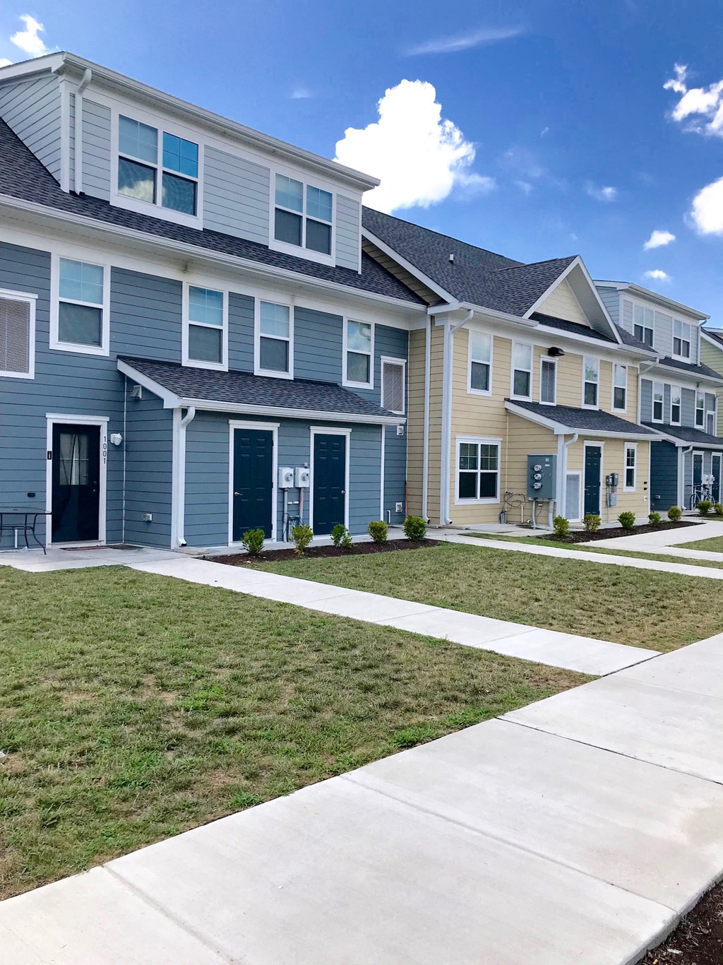 a row of blue houses with a sidewalk and grass