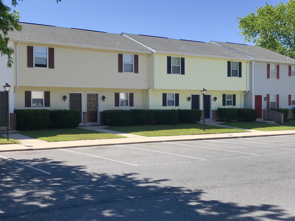Apartment building with a parking lot in front.
