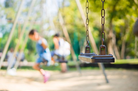A swing set with a blurred child in the background.