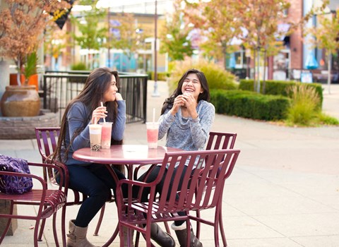 two women sitting at a table eating ice cream