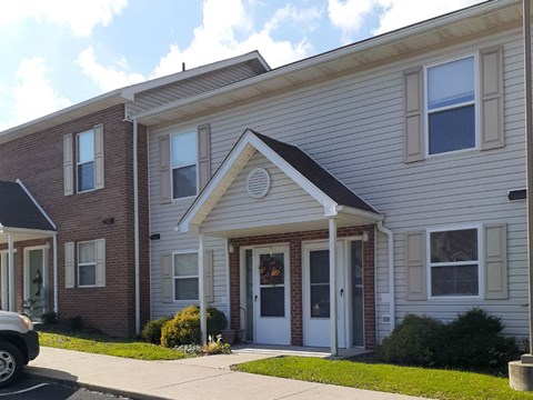 the front of a white and brick apartment building