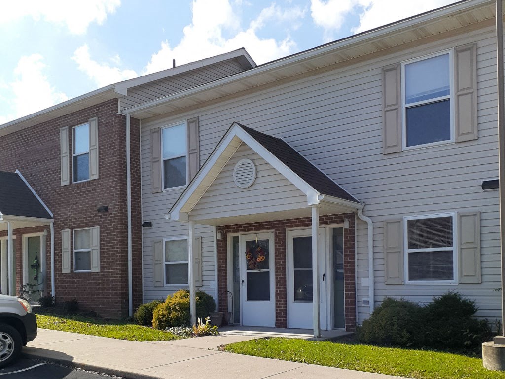 the front of a white and brick apartment building