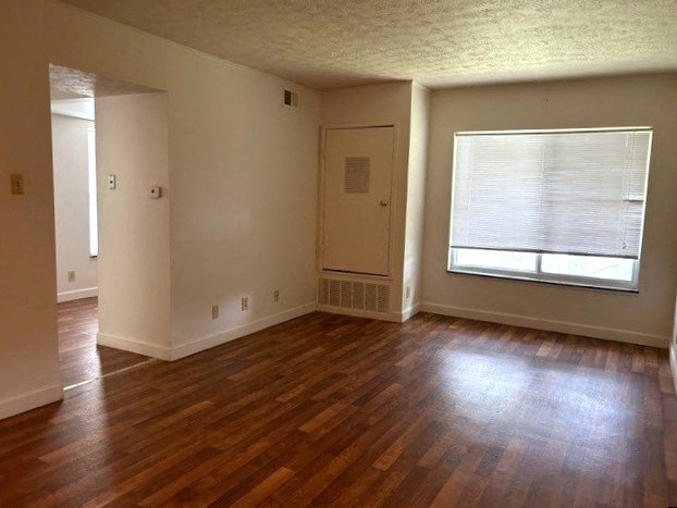 an empty living room with a hard wood floor and a window