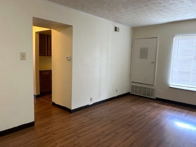 an empty living room with wood floors and a white door