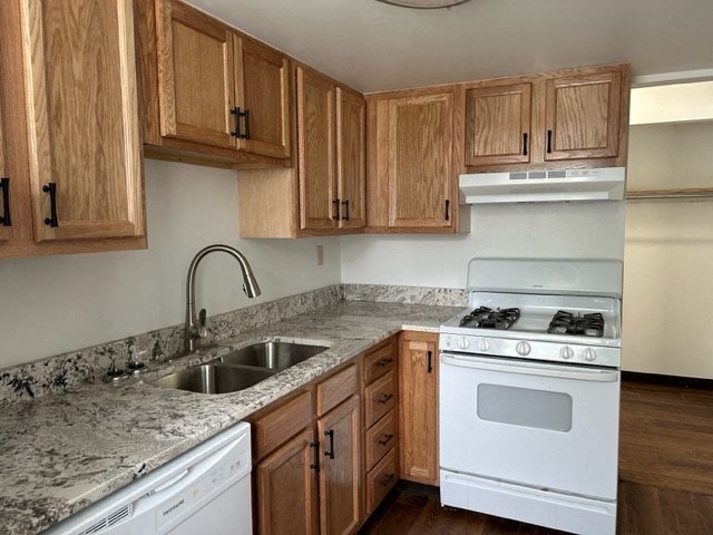 a kitchen with wooden cabinets and a white stove and sink