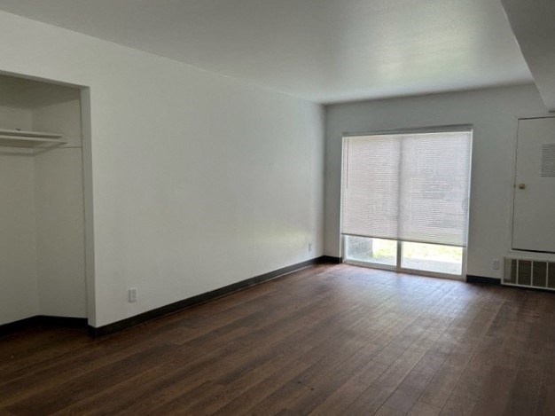 an empty living room with wood floors and a window