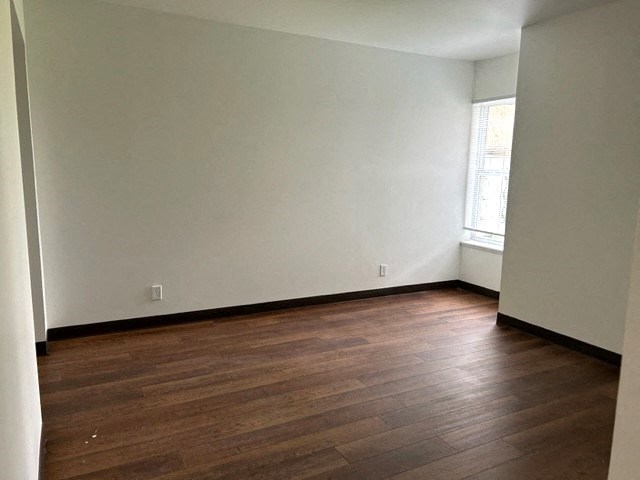 an empty room with wooden floors and a window