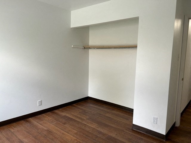 an empty room with a white wall and wood floor