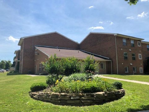 A large brick building with a landscaped front yard.