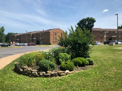 A large grassy area in front of a building with a small garden in the foreground.