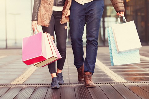 A man and woman walking together carrying shopping bags.