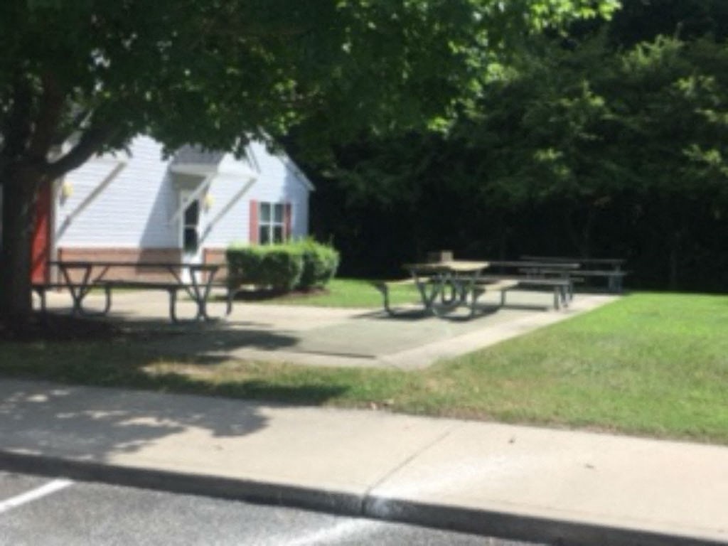 A park with picnic tables and a house in the background.