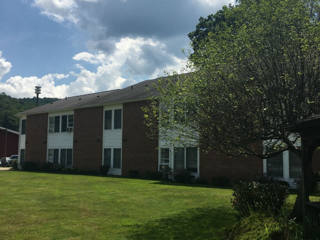 a brick building with a green lawn and trees