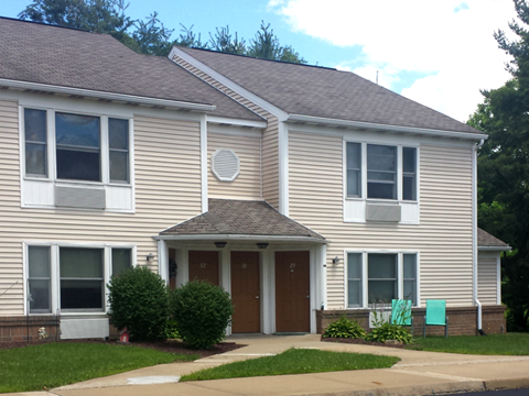 A two-story house with a brown door and a small porch.