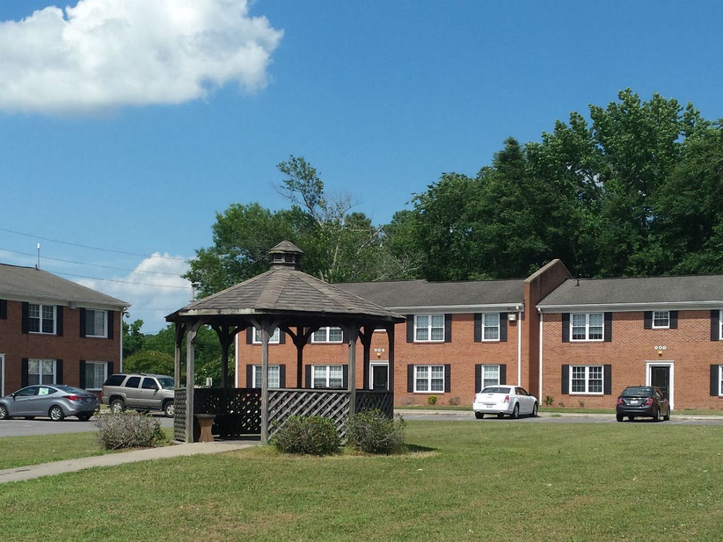 a gazebo in a yard in front of a brick building
